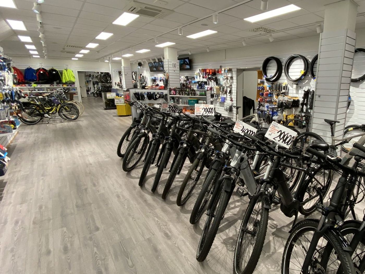 Inne i butikken: en lang rad med elsykler, og dekk, hjelmer og utstyr på veggene